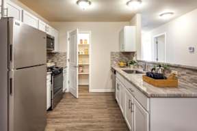 A kitchen with a refrigerator, microwave, oven, and sink.