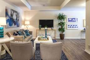 A living room with a grey couch, a white coffee table, and a painting on the wall.