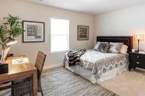 A bedroom with a bed, chair, and lamp.