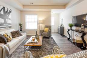 A living room with a white couch, a coffee table, and a television.