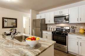 A kitchen with a bowl of fruit on the counter.
