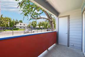 A red wall with a white door and a tree in the background.