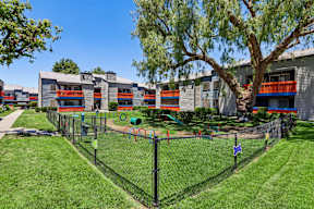 A playground with a green lawn and a fence in front of a building.