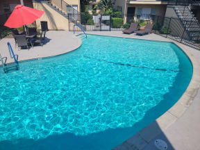 a large swimming pool with chairs and an umbrella