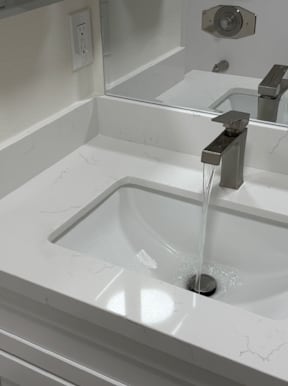 A white sink with a faucet running water into it.