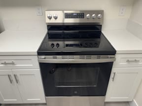 A modern kitchen with a black oven and white cabinets.