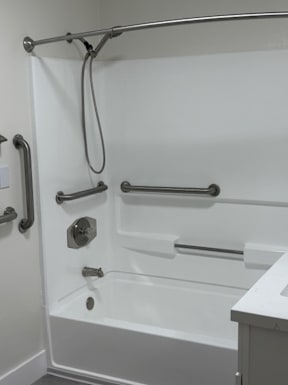 A white bathtub with a shower head and hand held shower.