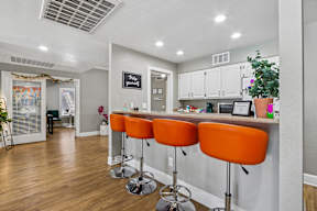 A kitchen with a bar area featuring orange stools.