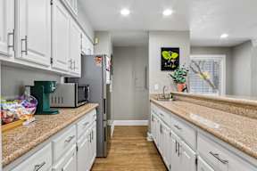 A kitchen with white cabinets and granite countertops.