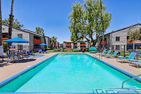 A swimming pool surrounded by lounge chairs and umbrellas.