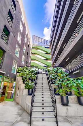 A staircase with a metal railing leads up to a green area.