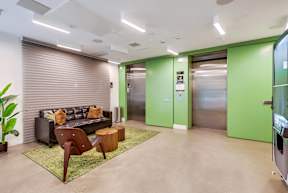 A modern office lobby with a green wall and a wooden chair.