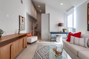 A living room with a couch, a coffee table, and a painting on the wall.