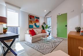 A modern living room with a white sofa and a large abstract painting on the wall.