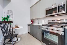 A modern kitchen with a black chair and a white table.