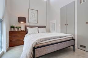 A bedroom with a bed, nightstand, and a framed picture on the wall.