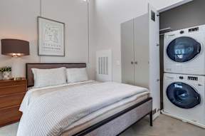 A modern bedroom with a washing machine in the doorway.