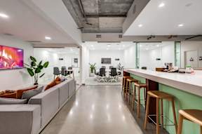 A modern office space with a long white couch, a green wall, and a large painting on the wall.