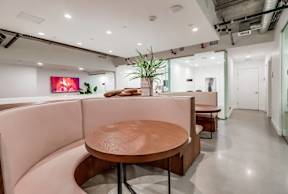 A modern office space with a wooden table and pink booths.