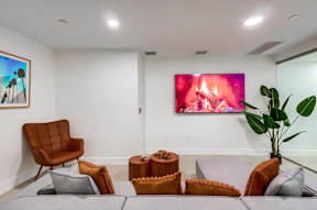 A living room with a brown chair, a grey couch, and a painting on the wall.