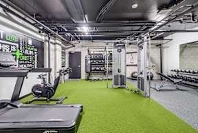 A gym with a green floor and a variety of equipment.