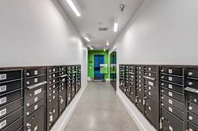 A long hallway with black filing cabinets on either side and a green door at the end.