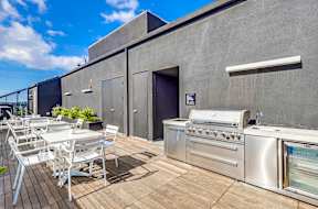 A patio with a grill and chairs.
