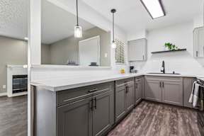 A kitchen with a white countertop and grey cabinets.