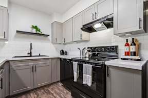 A kitchen with black appliances and white walls.