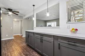 A kitchen with a white counter top and grey cabinets.