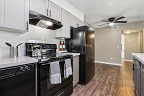 A modern kitchen with black appliances and wooden floors.