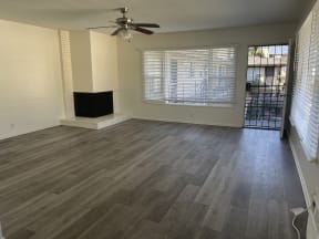 an empty living room with wood flooring and a ceiling fan