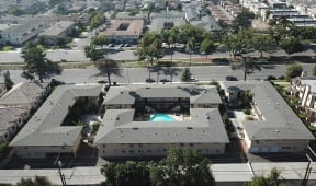 A bird's eye view of a apartment residential area with a swimming pool in the center.