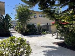 an apartment patio in front of a building with trees and plants