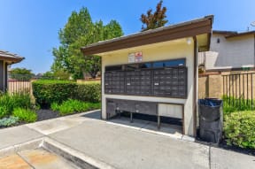 a mailboxes with a trash can in front of it