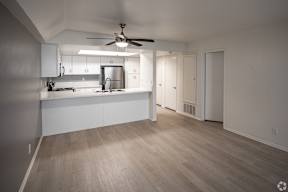 A kitchen with a refrigerator, sink, and cabinets.