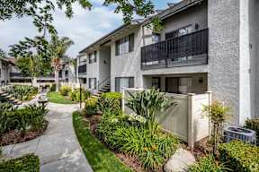 A concrete pathway leads to a building with a balcony.