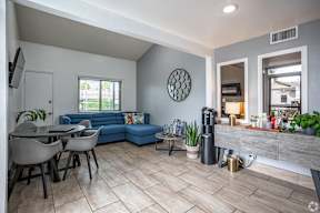 A living room with a blue couch and a television on the wall.