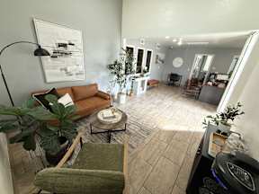 A living room with a green chair and a brown couch.
