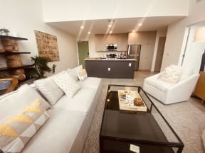 a living room with a couch and a coffee table in front of a kitchen