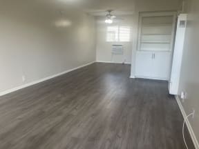 an empty living room with wooden floors and a ceiling fan