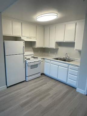 A kitchen with white appliances and cabinets.