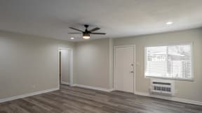 A room with a ceiling fan and a window with blinds.