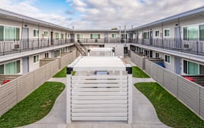 A white gate blocks the entrance to a courtyard between two rows of townhouses.