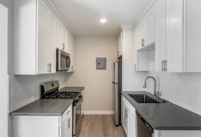 A kitchen with white cabinets and a black countertop.
