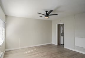 A room with a ceiling fan and a door leading to another room.