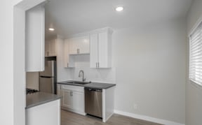 A kitchen with white cabinets and a stainless steel sink.
