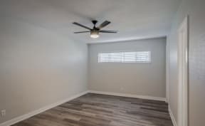 A room with a ceiling fan and a window with blinds.
