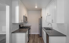 A kitchen with white cabinets and a black countertop.
