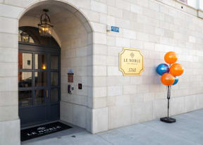 the front of a building with a black door and orange and blue balloons